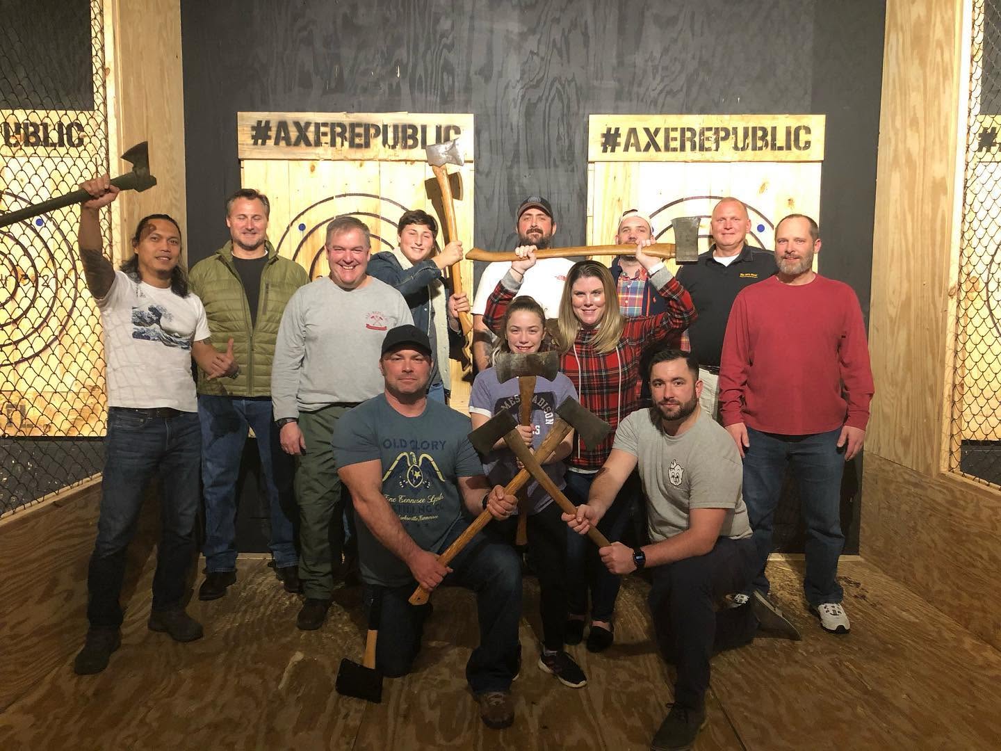 Group of people posing with axes at an indoor axe throwing venue.