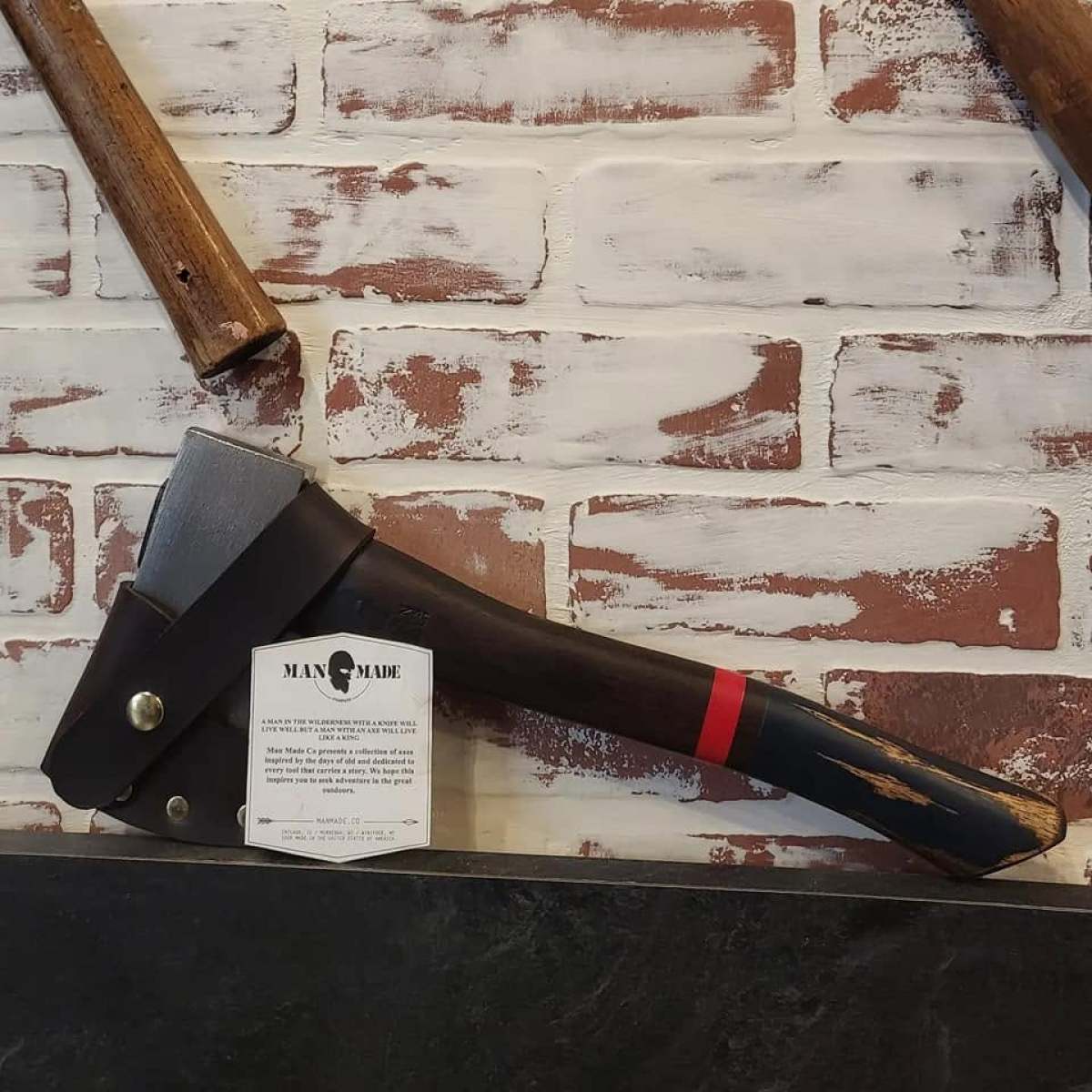 Axe with black handle on brick wall display.