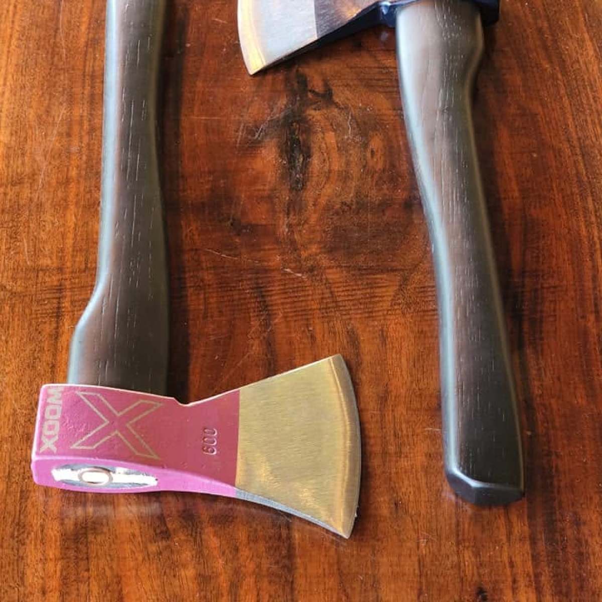 Two axes with colored heads on a wooden surface.