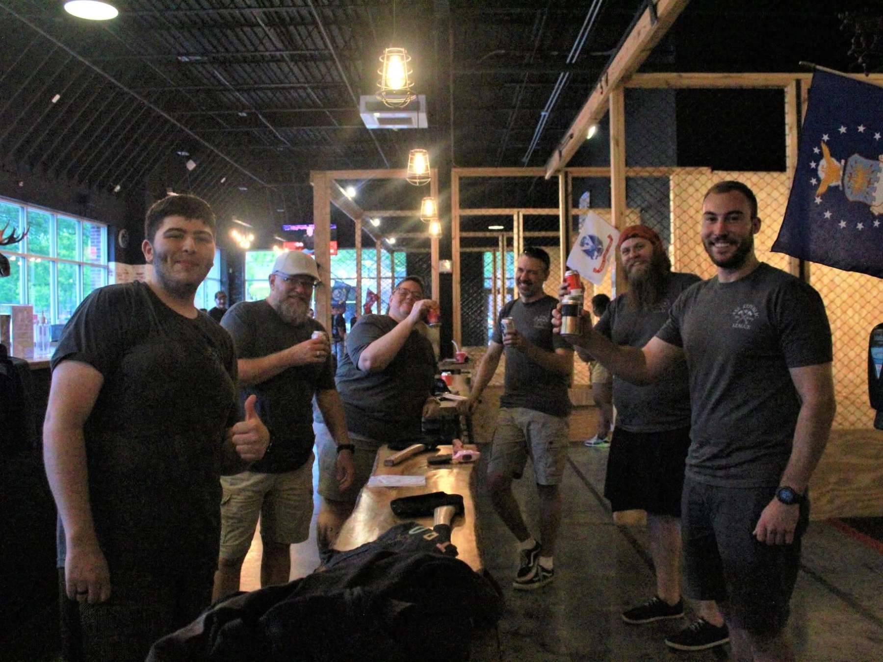 Group of people inside a dimly lit venue, smiling and giving thumbs up.