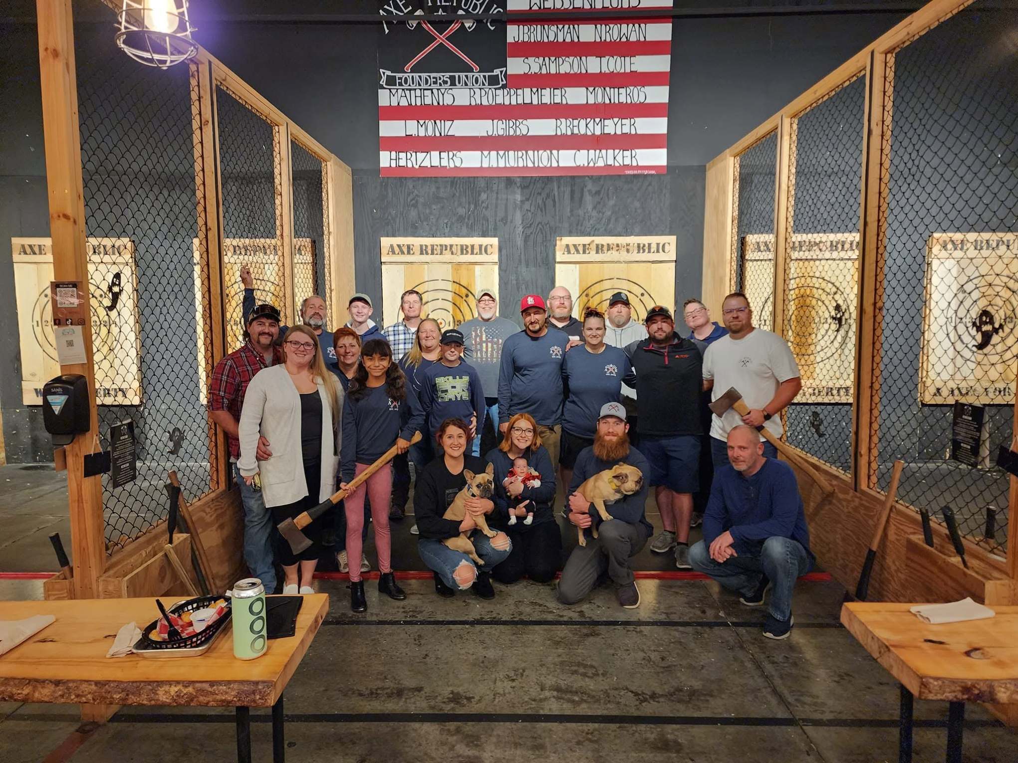 Group of people posing in an axe-throwing venue with wooden targets.
