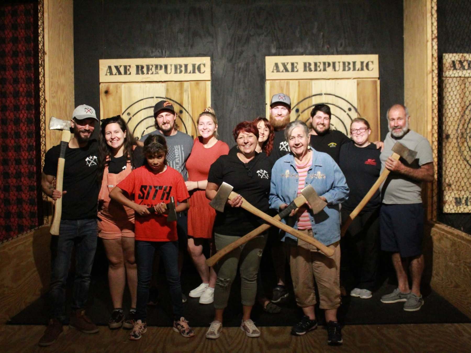 Group holding axes posing in front of wooden targets at Axe Republic.