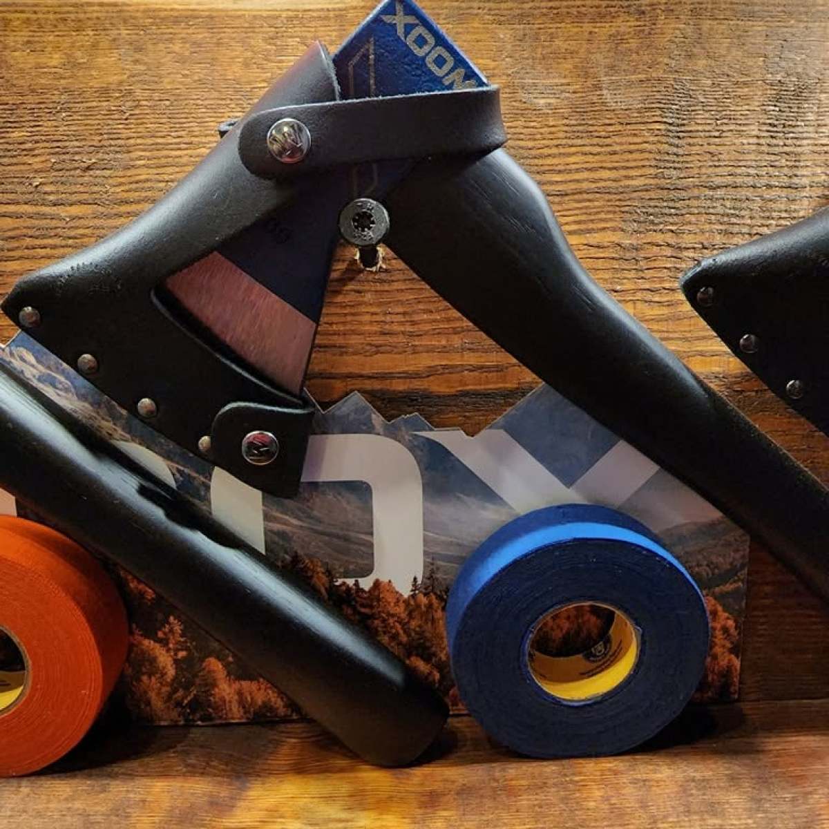 Two folding axes and rolls of colorful tape on a wooden surface.