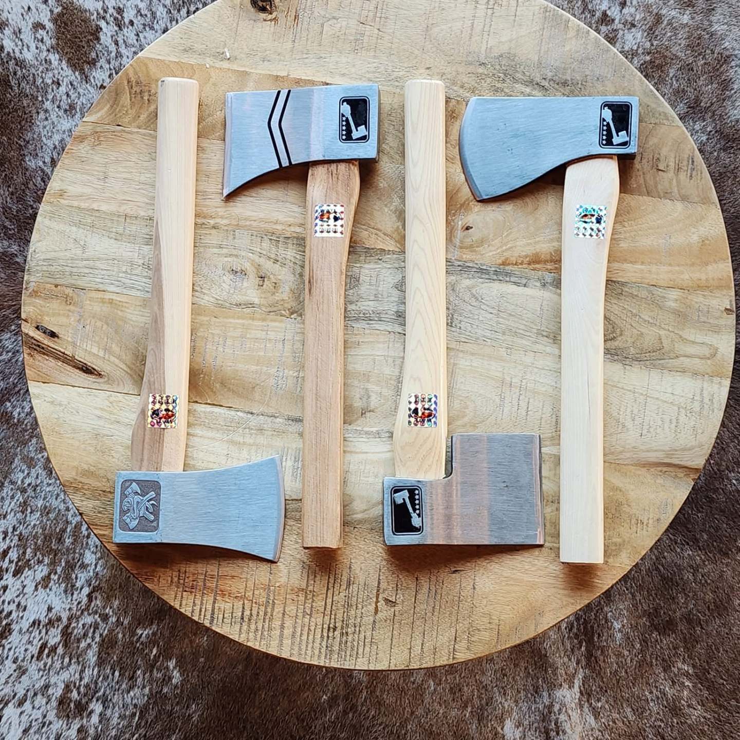 Four axes with wooden handles on a round wooden table.