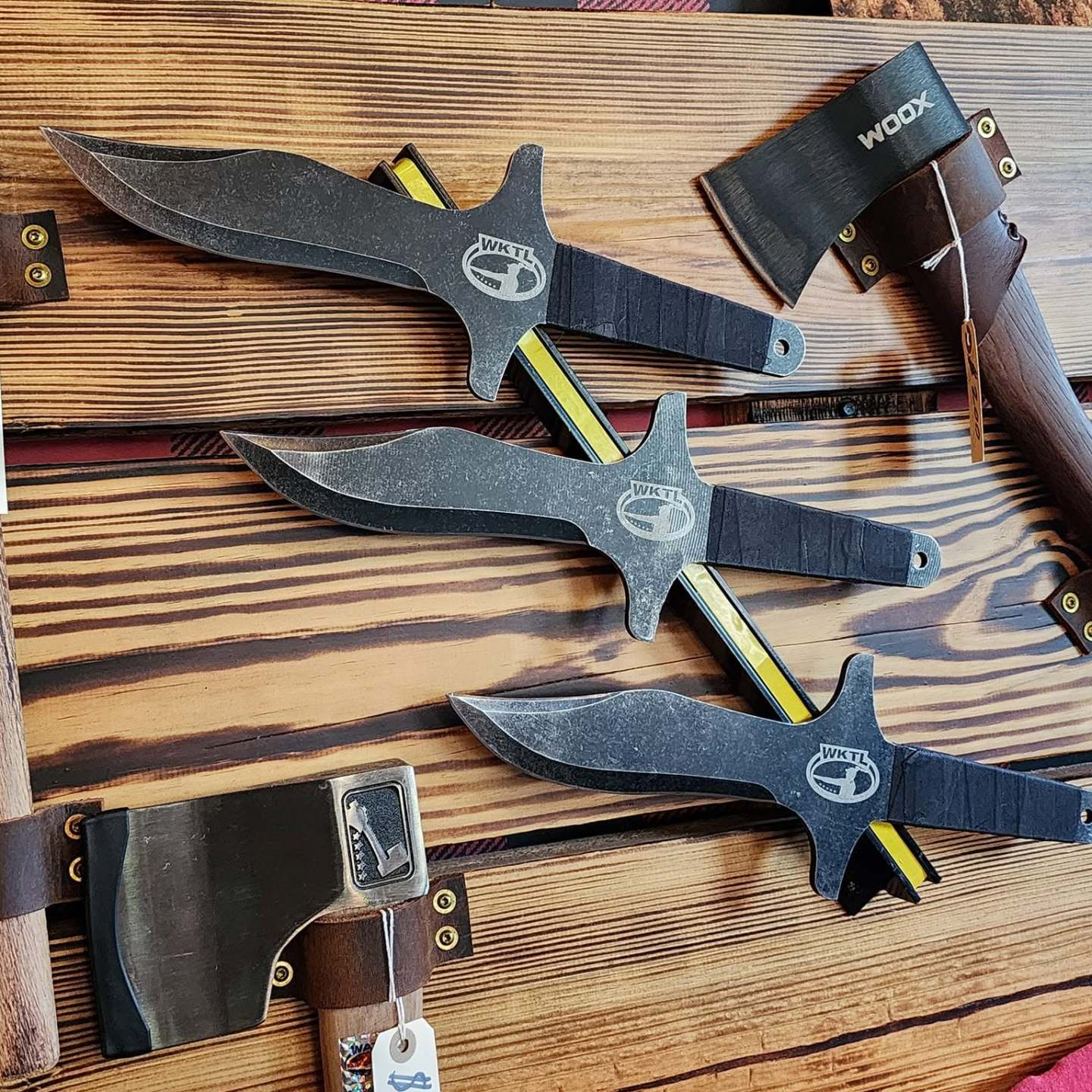 Three knives and two axes displayed on a wooden board.
