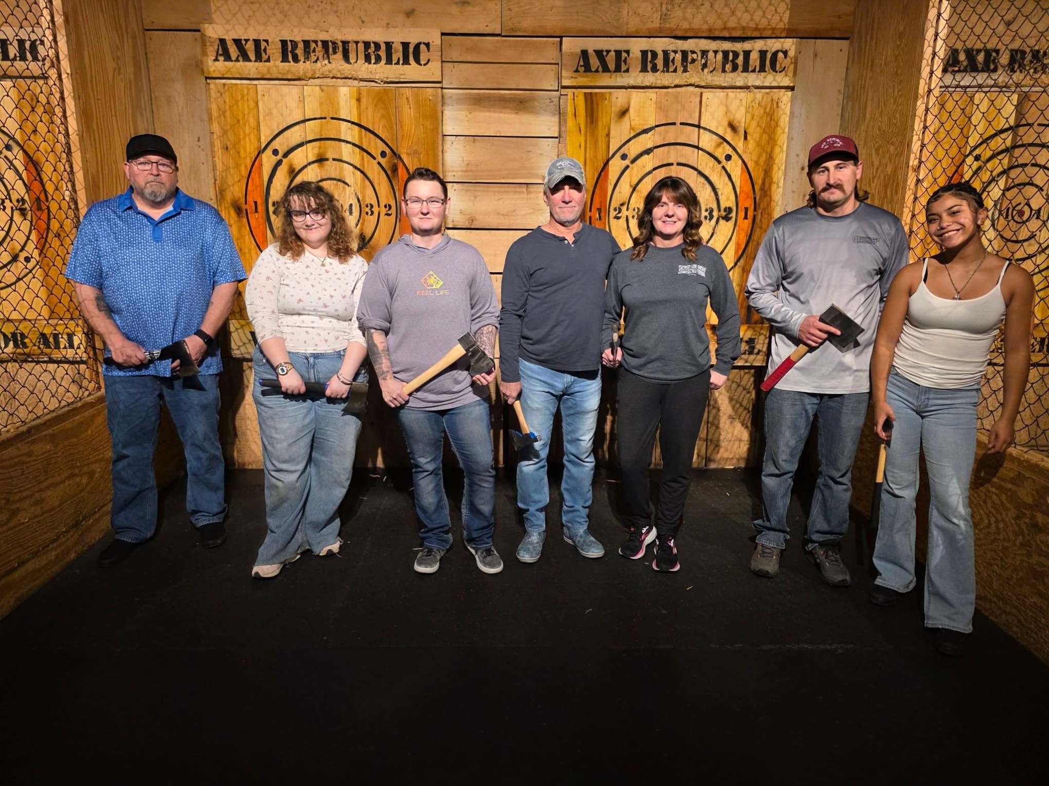 Group of people holding axes in front of target boards at Axe Republic.