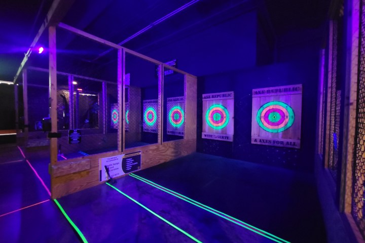 Indoor axe throwing lanes with neon targets and dim lighting.