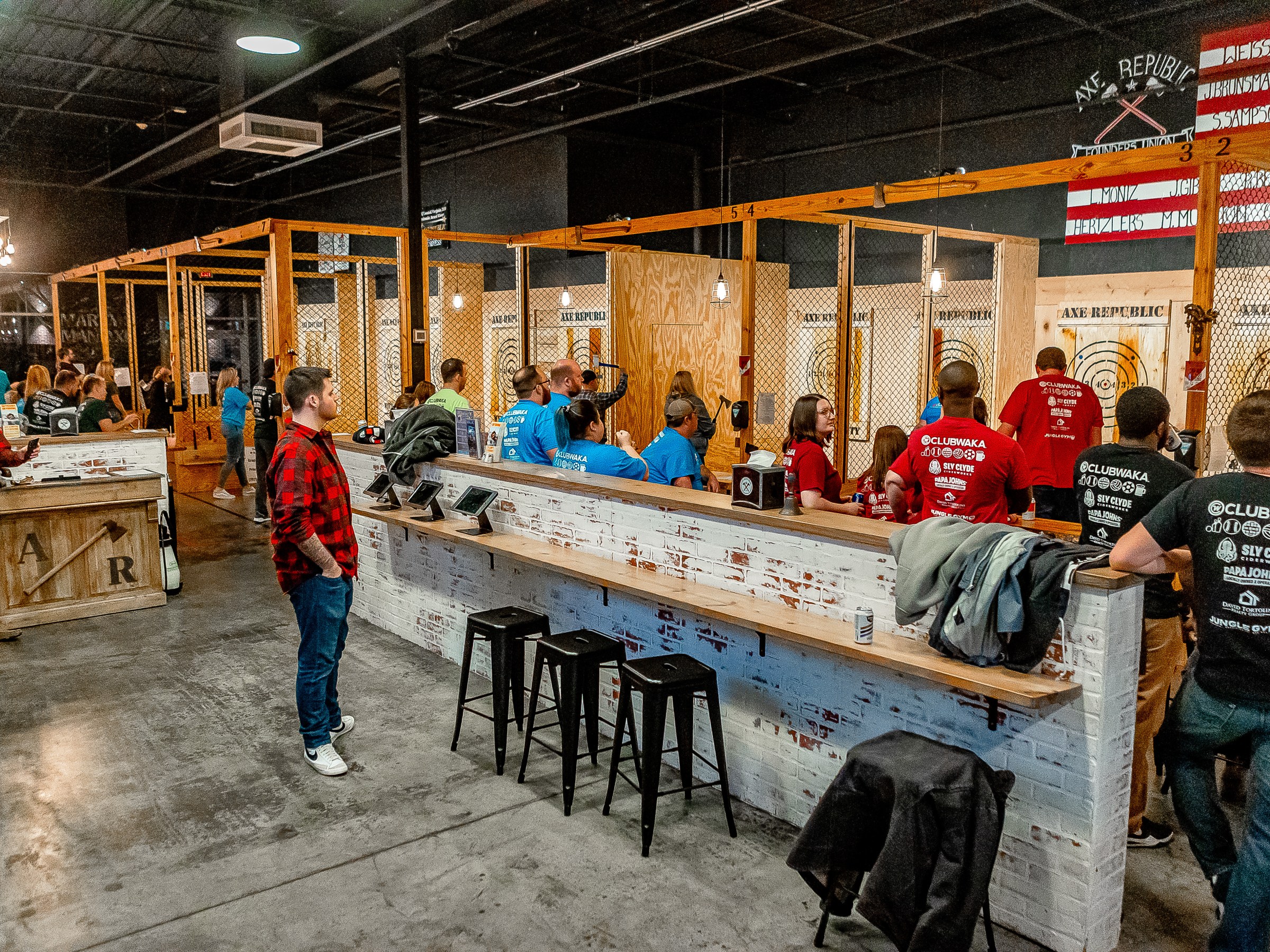 People in a large indoor axe-throwing venue with wooden lanes.