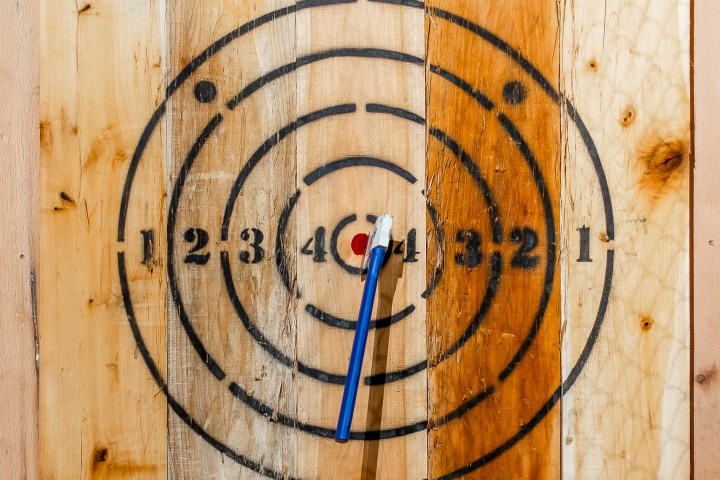 Wooden target board with a blue axe in the bullseye.
