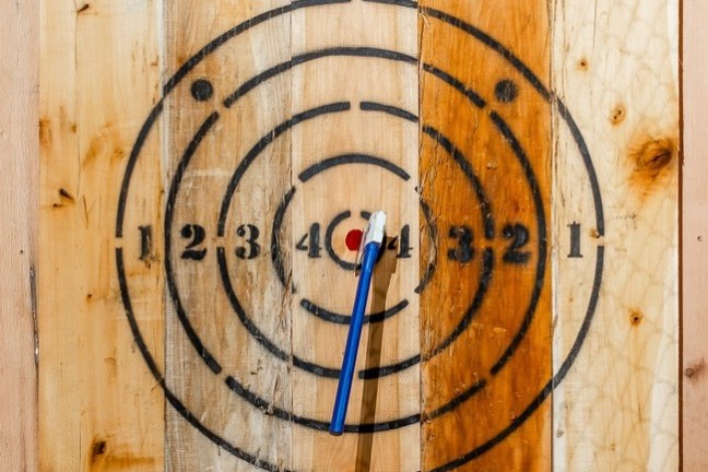 Wooden axe throwing target with a blue axe in the bullseye.