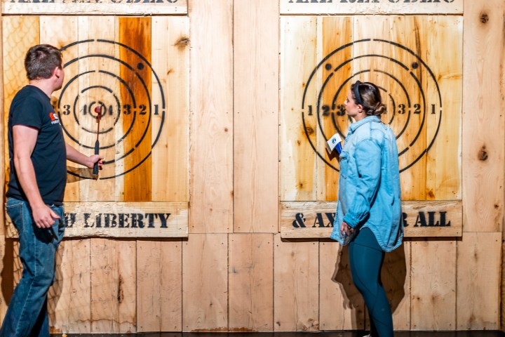 Two people near wooden targets for axe throwing.