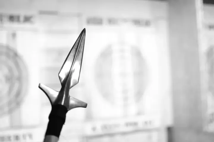 Close-up of a spearhead with blurred target boards in the background.